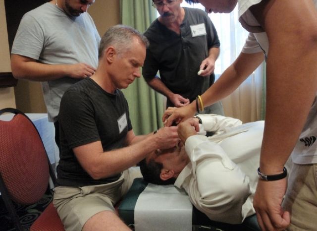 A doctor placing the CFR balloon instrument while a colleague looks on at a Cranial Facial Release seminar