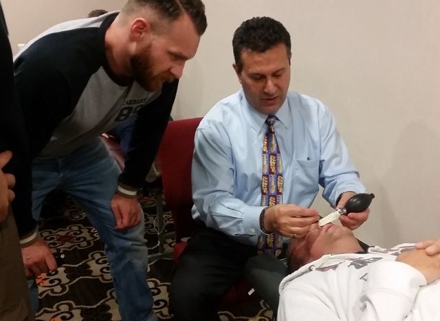 A doctor performing the Cranial Facial Release technique on a reclined patient at a certification seminar