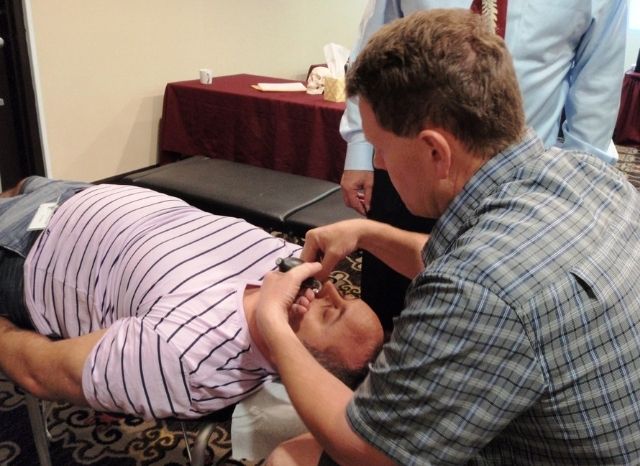 A CFR doctor treating a patient lying on a table during a Cranial Facial Release seminar