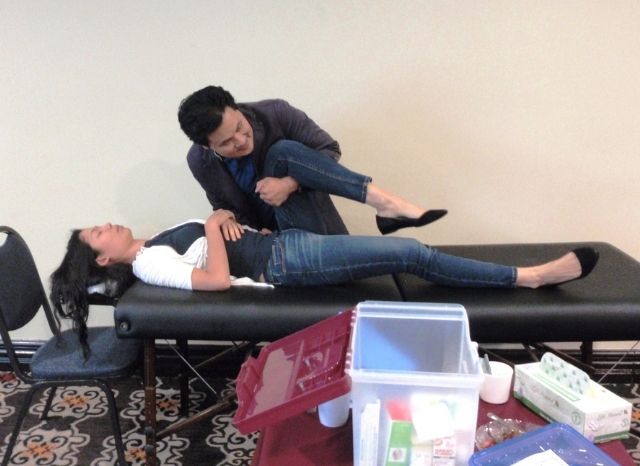 The CFR treatment kit open beside the table while a practitioner works with a patient at a seminar