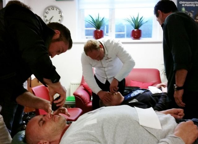 A CFR instructor treating a patient on the table while seminar attendees observe