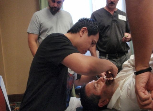 A doctor performing the Cranial Facial Release technique on a patient lying on a treatment table at a CFR seminar